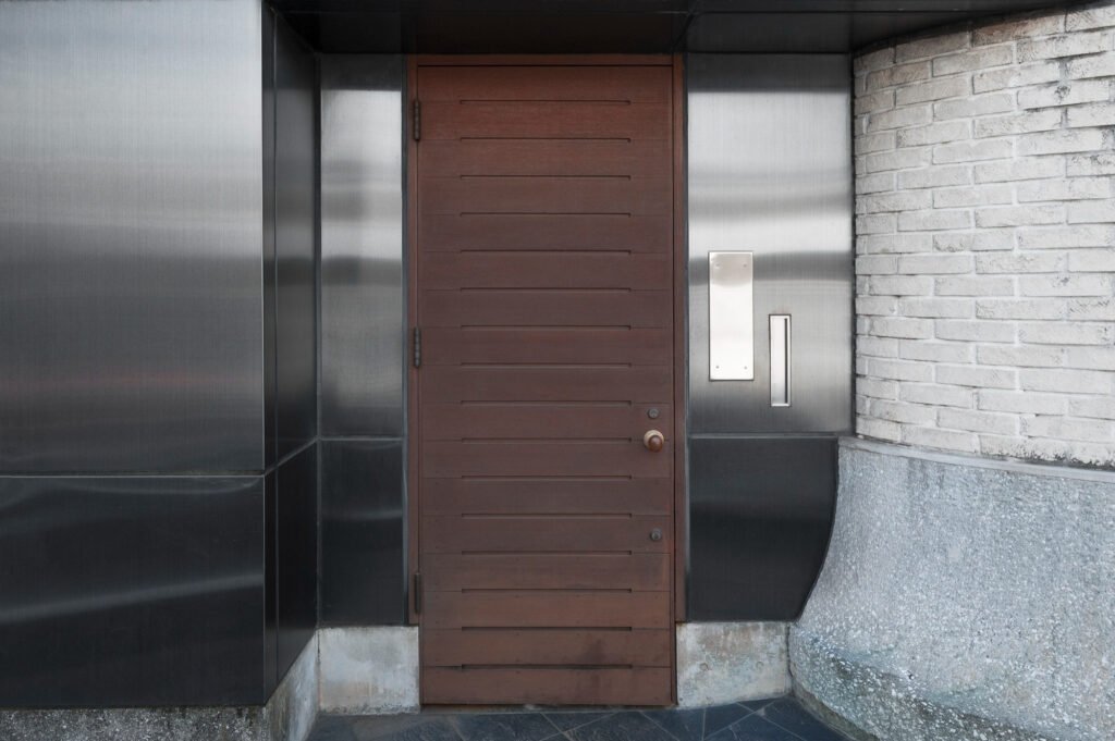 Installation de porte blindée en façade avec finition bois sur entrée contemporaine
