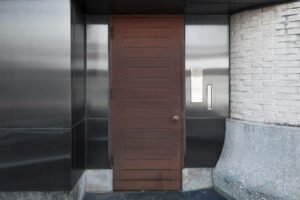 Installation de porte blindée en façade avec finition bois sur entrée contemporaine