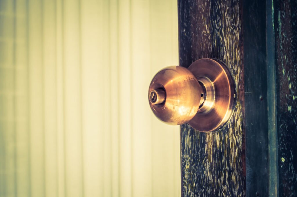 Grosse poignée en laiton sur une porte en bois, élément surveillé par un serrurier pour copropriété lors d’une maintenance.