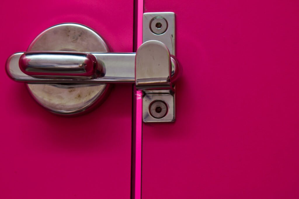 Verrou de sécurité métallique sur une porte rose, installé par un serrurier pour copropriété dans un local technique.