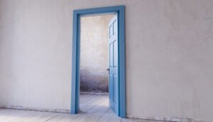 porte bleue entrouverte dans un intérieur vide après une ouverture porte claquée sans clé.